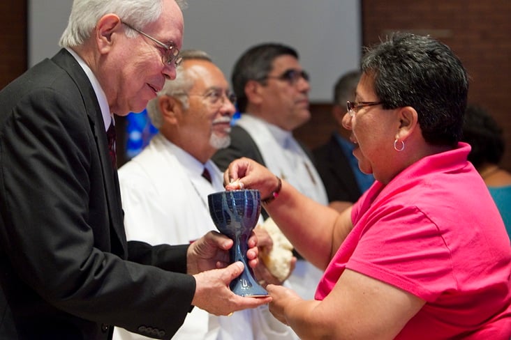 The Rev. Noé Gonzales (left) offers Holy Communion to Nohemi Ramirez during worship  in El Paso, Texas. Photo by Mike DuBose, United Methodist Communications. 